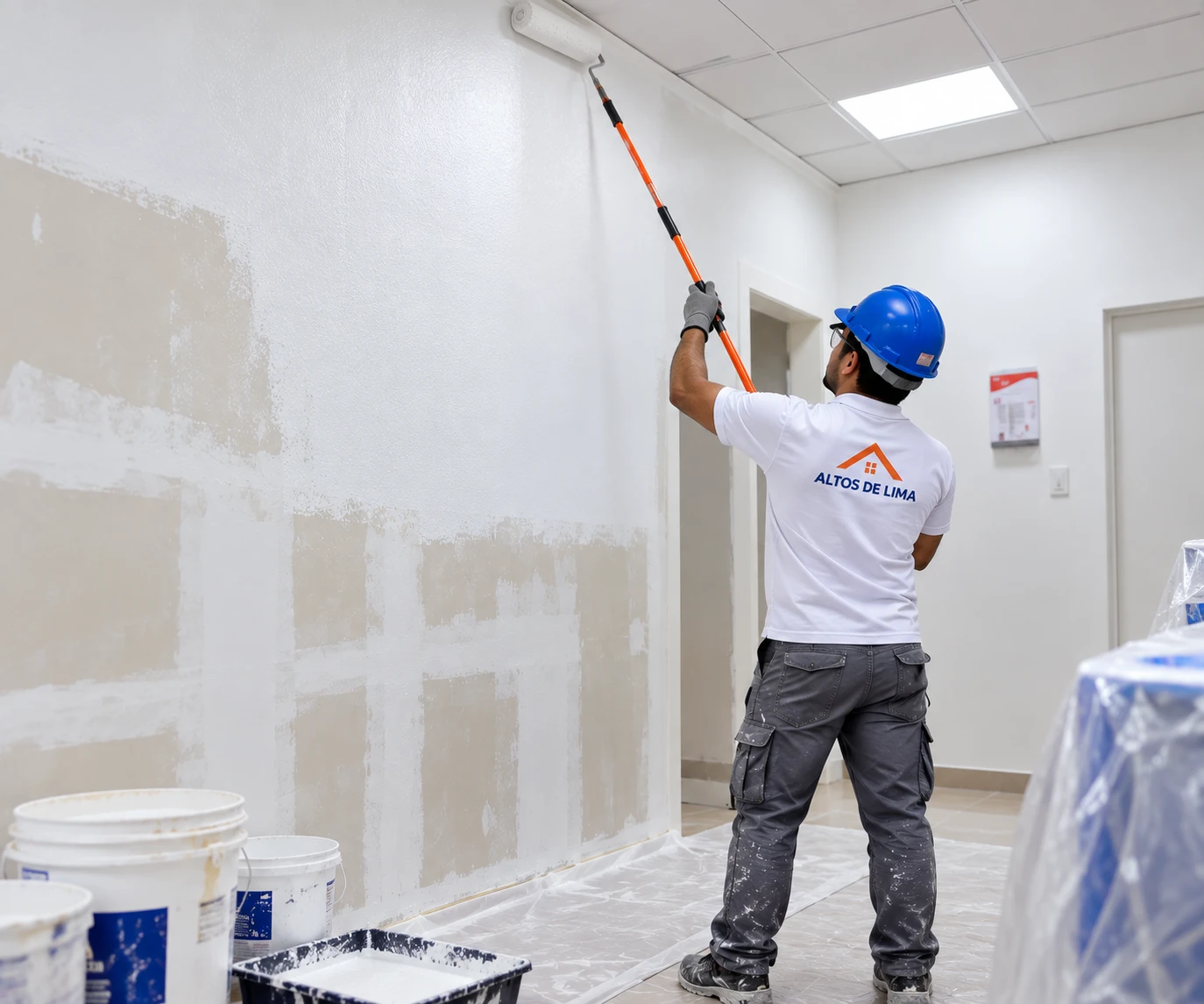 Pintor renovando una pared blanca en un ambiente interior